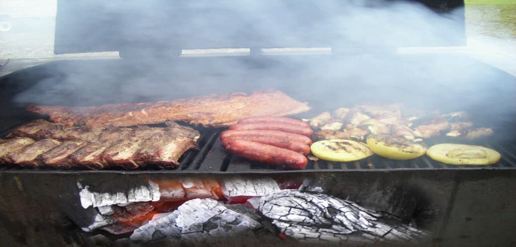 Full grill cookout with ribs, sausages, and squash over mesquite coals