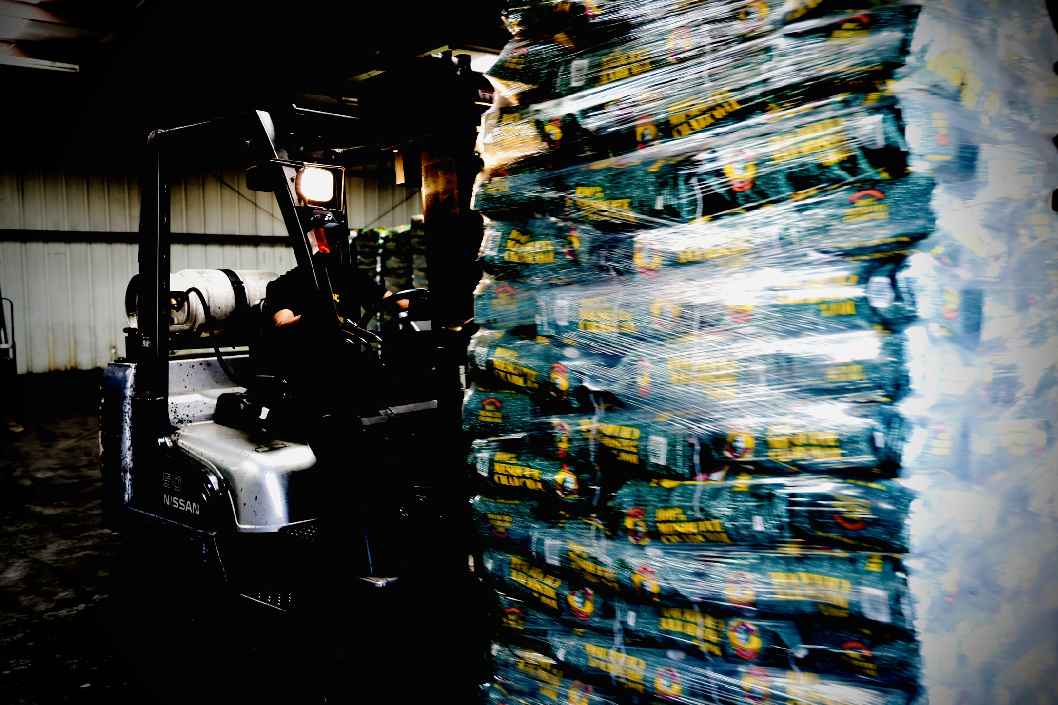 Forklift moving wrapped pallets of mesquite charcoal in the warehouse